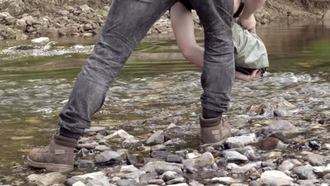 person walking in a river with a bag