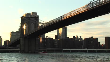 the camera shoots from waterlevel to the brooklyn bridge above and buildings beyond