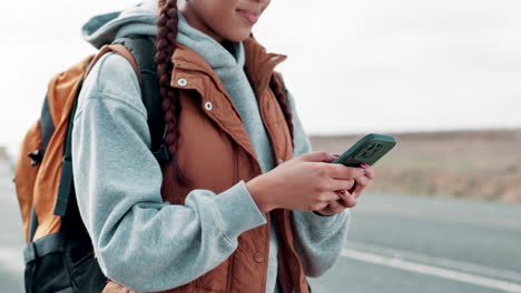 woman with backpack using phone on the road