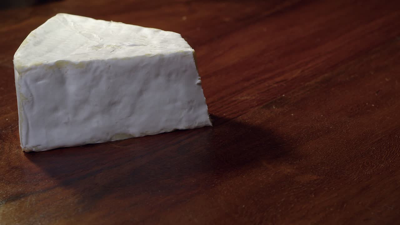 dos rebanadas de queso brie suave cortadas en un bloque de cuña en madera oscura