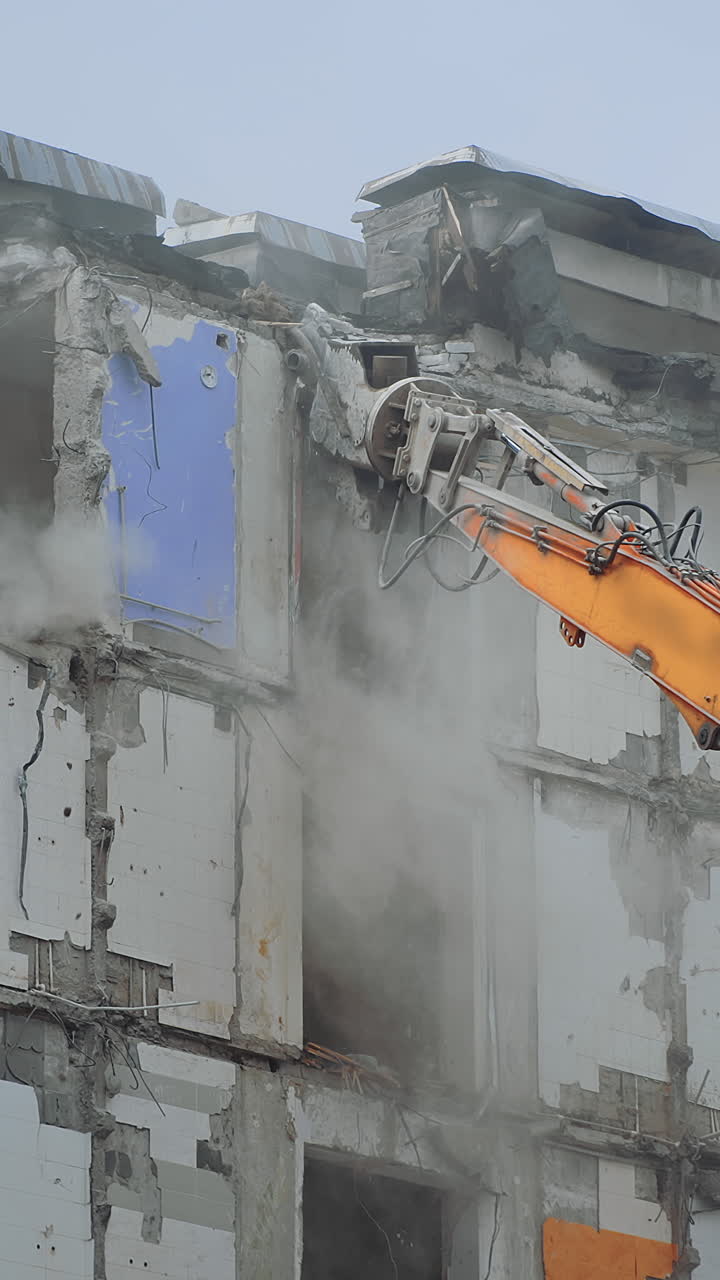 Excavator destroying demolished building. Breaking down old big house. Vertical video