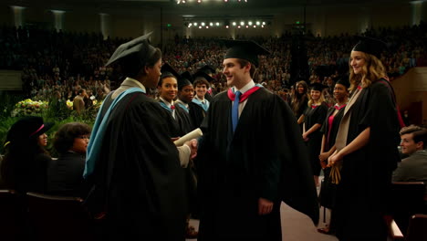 students graduating and receiving diplomas at a commencement ceremony