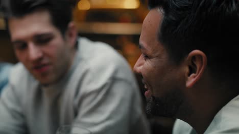 primer plano de un hombre multirracial bebiendo cerveza y amigos en el fondo