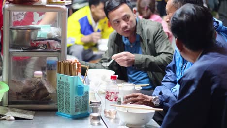 people enjoying street food in hanoi, vietnam