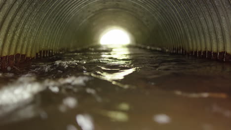 Surface-water-or-stormwater-runs-through-corrugated-overflow-pipe,-low-angle