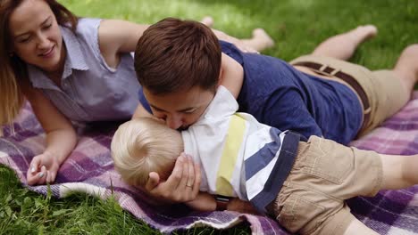 Kaukasisches-Paar-Hat-Eine-Schöne-Zeit-Im-Freien-Mit-Seinem-Sohn.-Auf-Einem-Plaid-Im-Park-Liegen.-Picknick.-Vater-Spielt-Mit-Dem-Sohn.-Umarme-Ihn,-Küsse-Ihn,-Spiele-Ein-Spiel.-Nahaufnahme