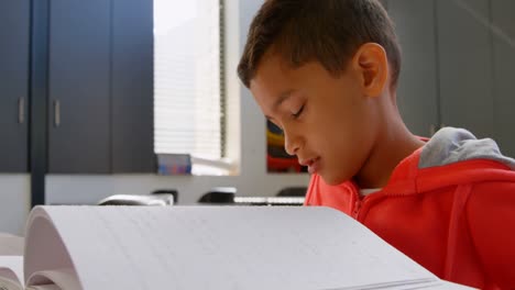Side-view-of-blind-Asian-schoolboy-hand-reading-a-braille-book-in-classroom-at-school-4k