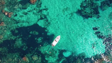 Toma-Aérea-De-Arriba-Hacia-Abajo-En-4k-De-Personas-Nadando-Junto-A-Un-Yate-En-El-Mar-Mediterráneo-Azul-Cristalino-Y-Turquesa-En-Mallorca,-España---Vacaciones-De-Lujo---Islas-Baleares