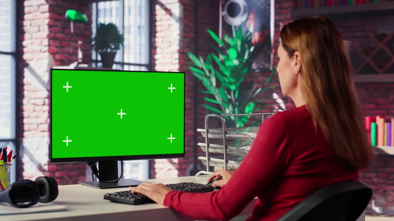 Woman working on a computer with a green screen