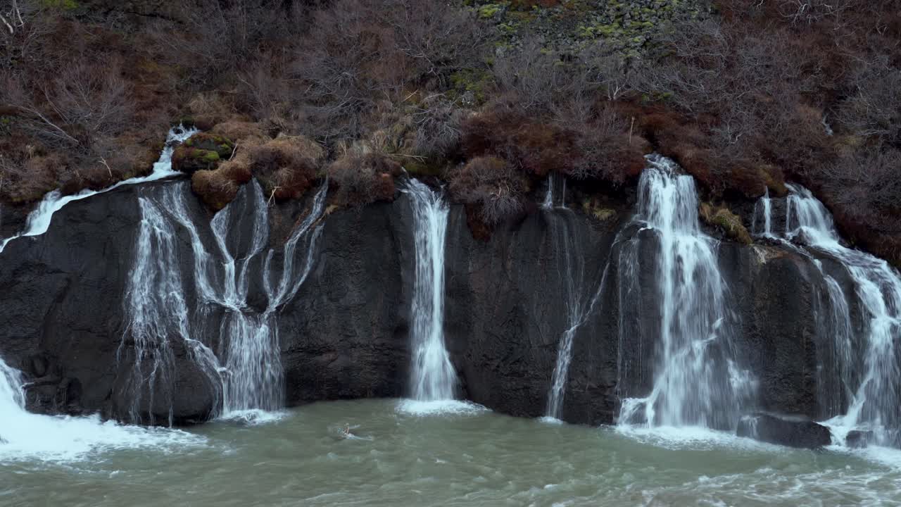 cascada de hraunfossar que desciende desde las repisas bajas de roca volcánica hasta el río hvita a través del campo de lava hallmundarhraun, creando un hermoso paisaje