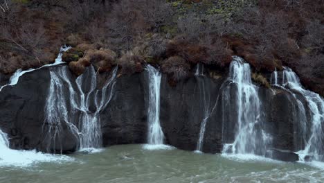 Cascada-De-Hraunfossar-Que-Desciende-Desde-Las-Repisas-Bajas-De-Roca-Volcánica-Hasta-El-Río-Hvita-A-Través-Del-Campo-De-Lava-Hallmundarhraun,-Creando-Un-Hermoso-Paisaje