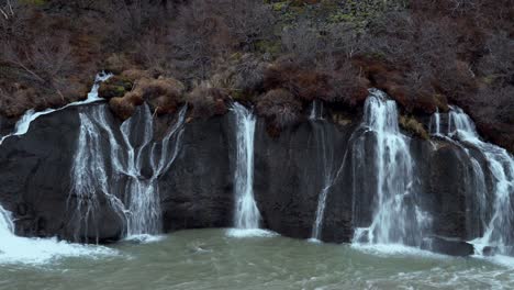 cascada de hraunfossar que desciende desde las repisas bajas de roca volcánica hasta el río hvita a través del campo de lava hallmundarhraun, creando un hermoso paisaje