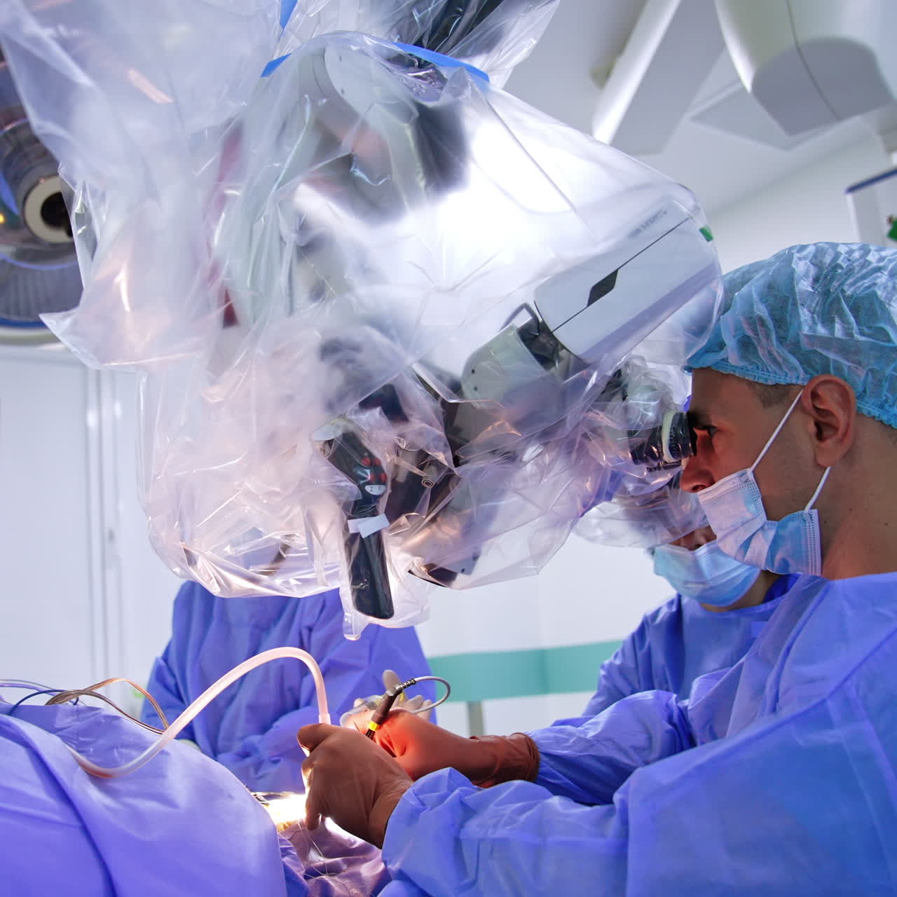 Male neurosurgeon performing operation using microscope. Doctor applies modern electric devices at surgery.