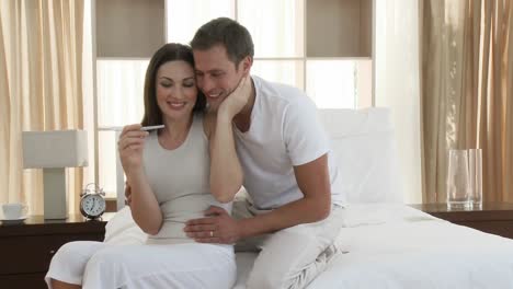 Happy-couple-looking-at-a-positive-pregnancy-test-in-bedroom