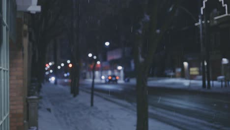 snowfall at night with bokeh vehicles traveling in road at background during winter