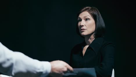 detective showing crime scene picture to female suspect, questioning in prison