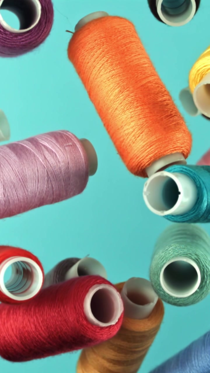 Colorful Sewing Thread Spools Floating Against a Blue Background