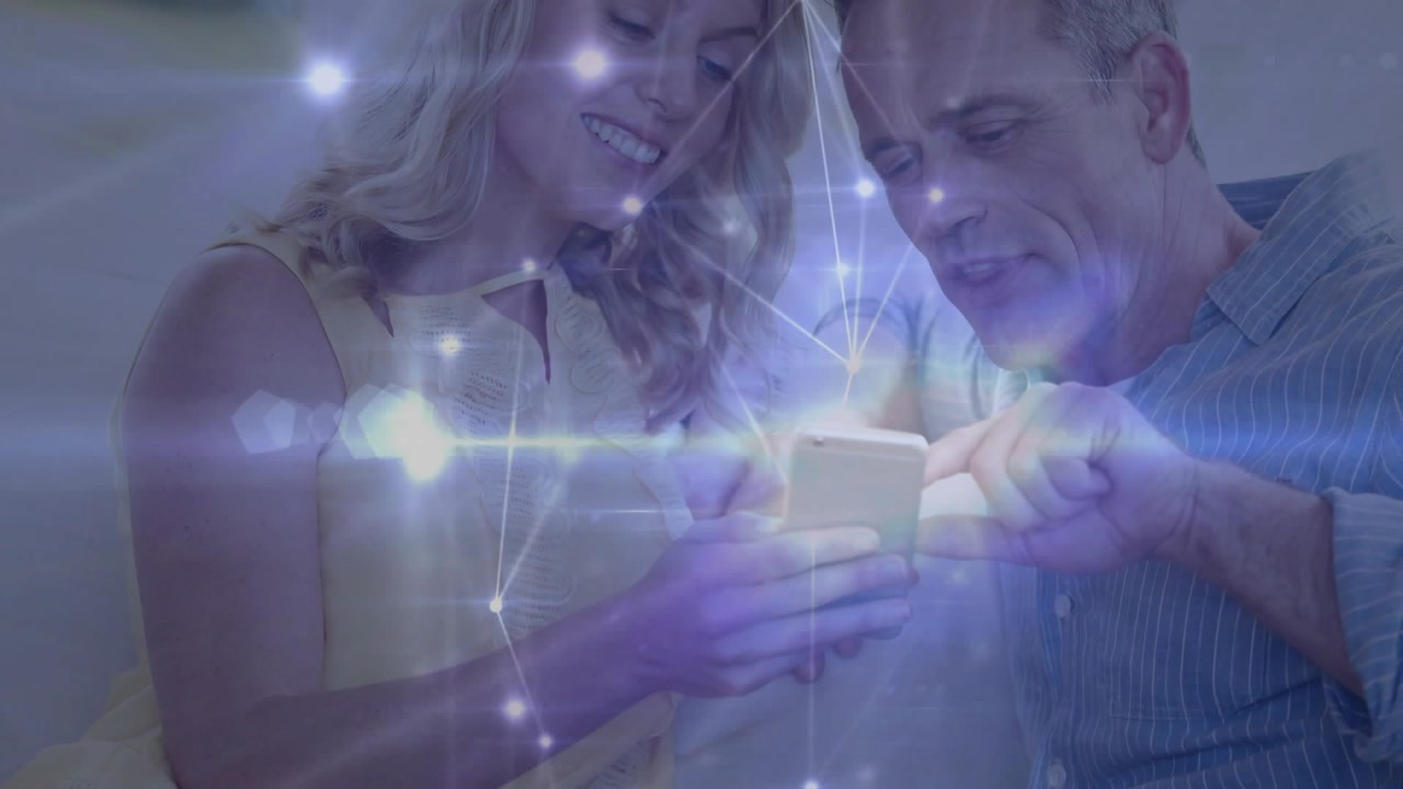 Man tapping smartphone screen and woman following content for viewing network overlay on sofa