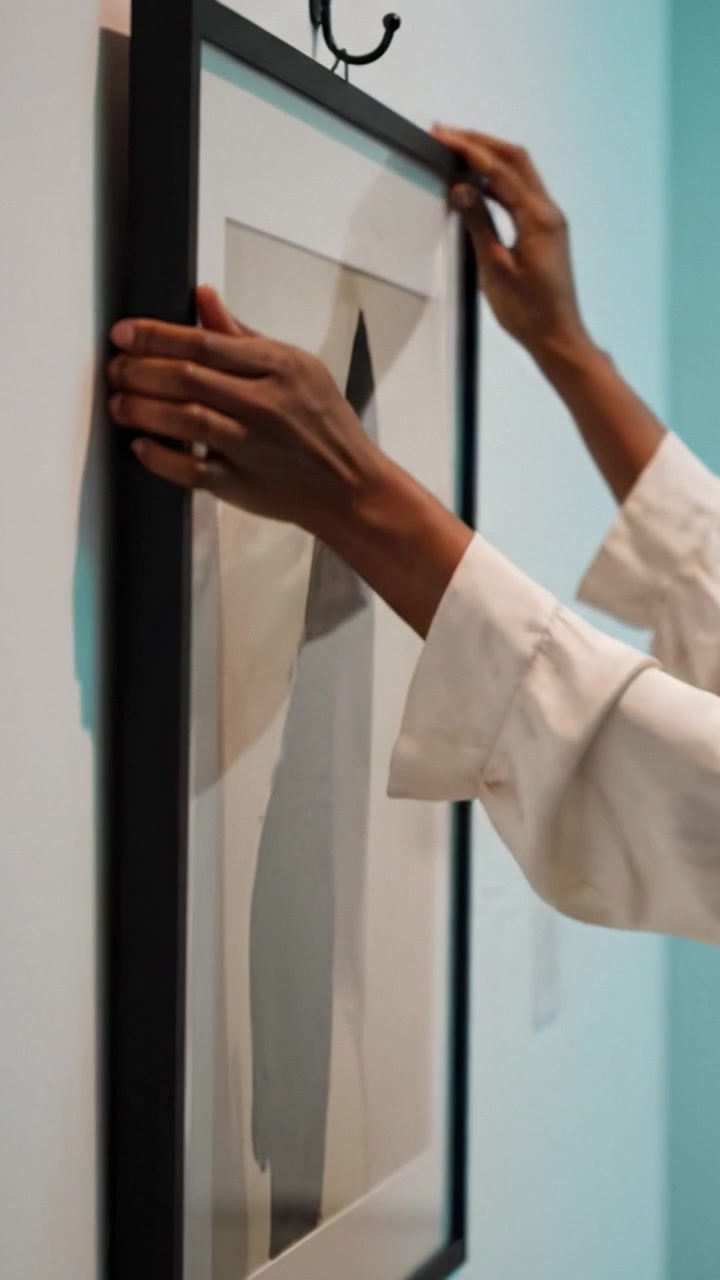 Gerahmte Kunst mit abstraktem Design an der Wand vor einem sanften Türkis-Hintergrund, die den eleganten Kontrast zwischen Schatten und Form in einem modernen Raum zur Geltung bringt.