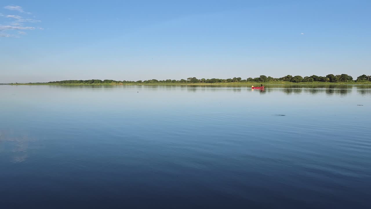Enjoy a peaceful canoe ride on the river in 4K at 60fps, as fishermen cast their lines and fish feed beneath the calm waters.
