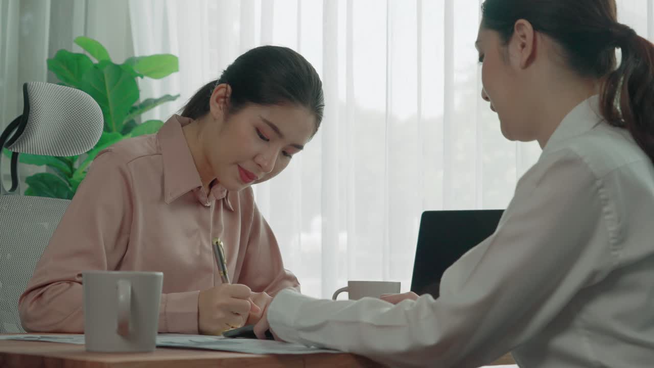 Two young enthusiastic businesswoman working together in the office workspace.