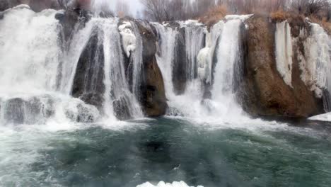 grandes cascadas con hielo colgando en los lados que se unen en una gran corriente en invierno