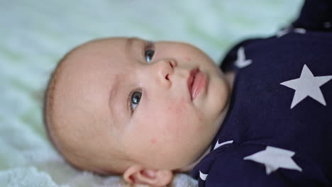 beautiful caucasian child lying peacefully on the bed face up. sweet baby boy resting quietly. close up. blurred backdrop.