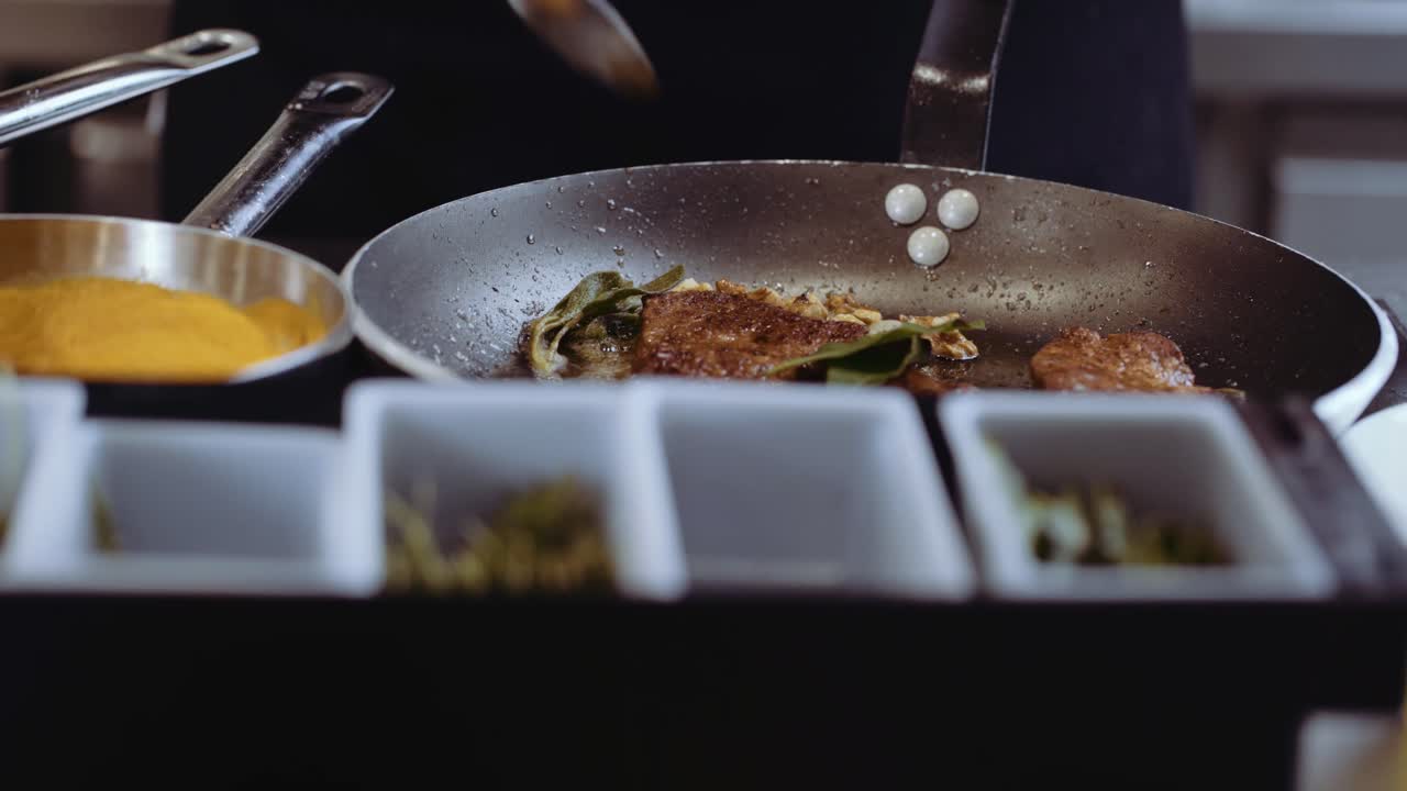 GROS PLAN : Chef cuisinier faisant cuire un steak dans une poêle, ajoutant des épices et des herbes.