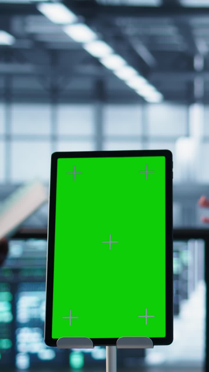 Vertical video Close up of chroma key tablet next to coworkers examining data center