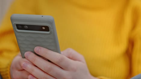 cropped view of a person in yellow sweatshirt is using cellphone