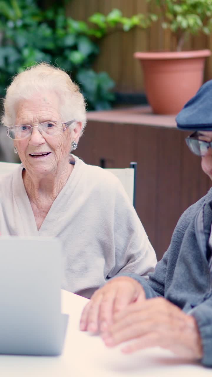 Elderly couple using a laptop in the garden