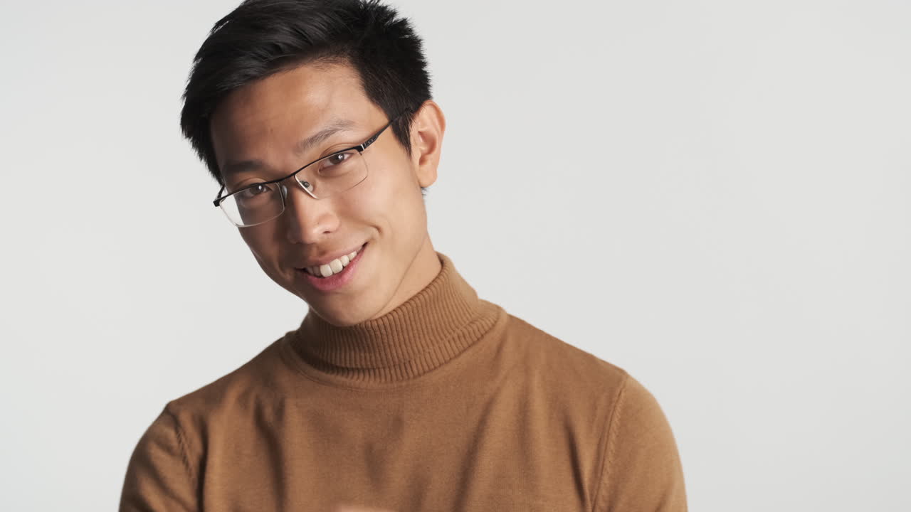 안경을 쓴 아시아인 남자가 카메라를 쳐다보고 있다.