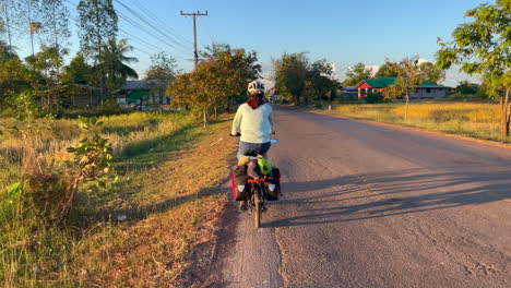 una filmación dinámica de una mujer que viaja en bicicleta con alforjas y comestibles en la parte trasera