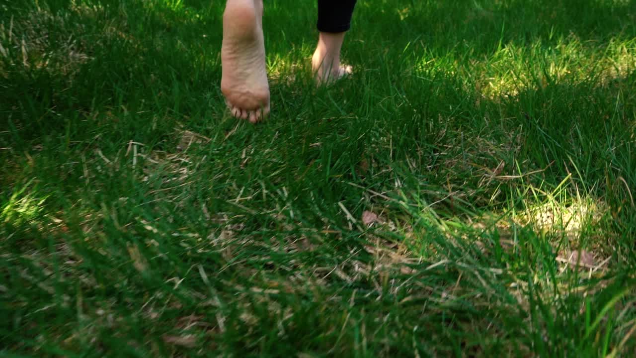 Girl's feet walking through grass in slow motion
