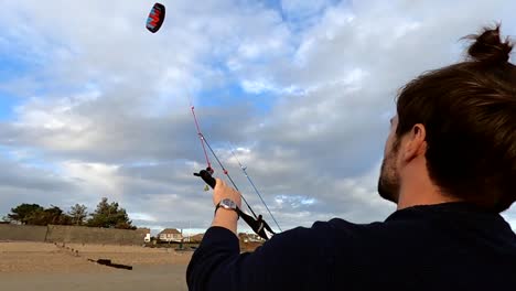 un primer plano de un hombre barbudo volando una cometa grande y colorida