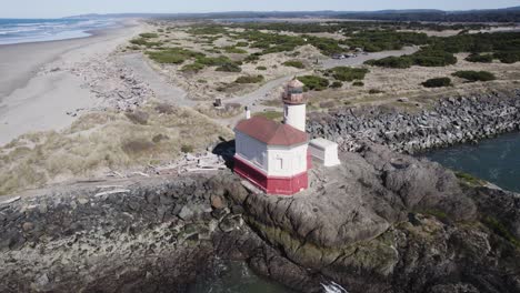 impresionante órbita aérea de 4k alrededor del faro del río coquille en bandon oregon rompiendo olas en el afloramiento rocoso en la desembocadura del río