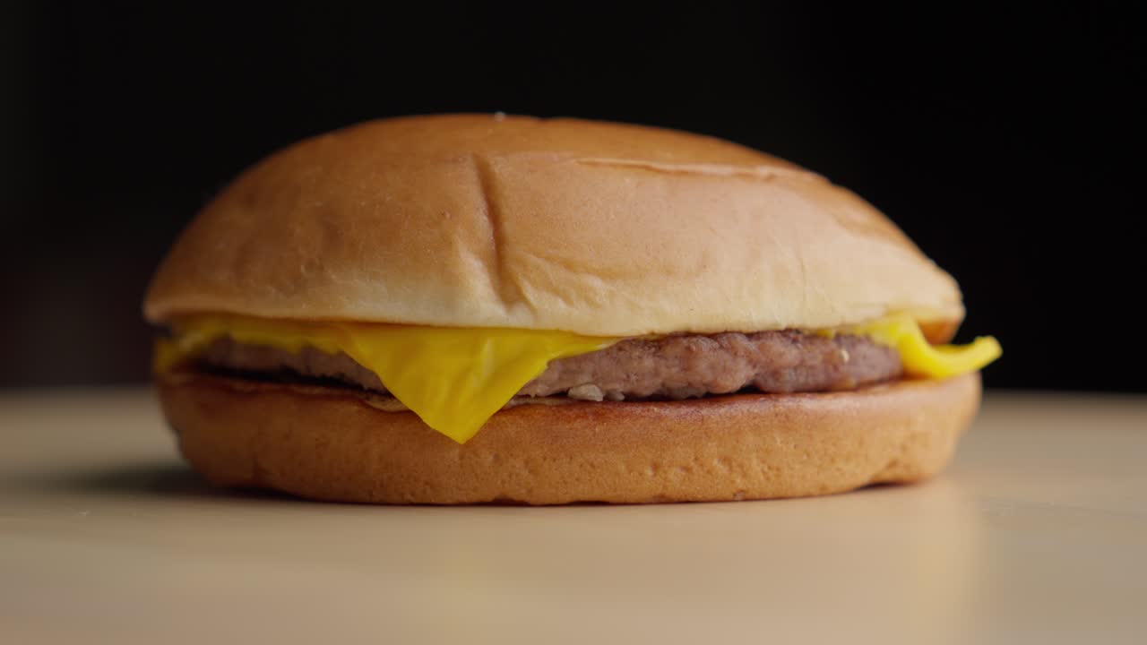 primer plano giratorio de una simple hamburguesa de queso con fondo oscuro