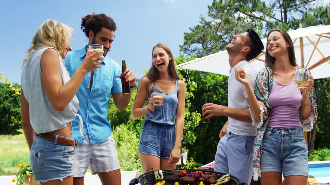 grupo de amigos bailando y tomando bebidas mientras preparan una barbacoa