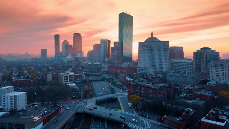 Autostrade a più corsie, ferrovie e superstrade con il traffico in movimento. Cielo rosa sopra il centro di Boston, Massachusetts, USA. Vista aerea