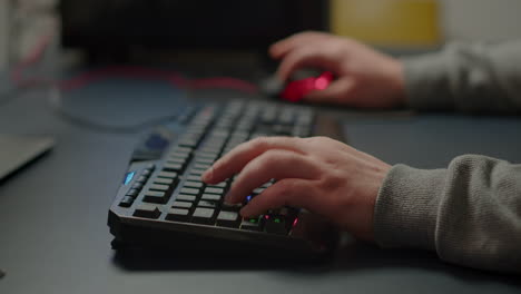 close-up on hands of pro cyber man playing video game using rgb keyboard