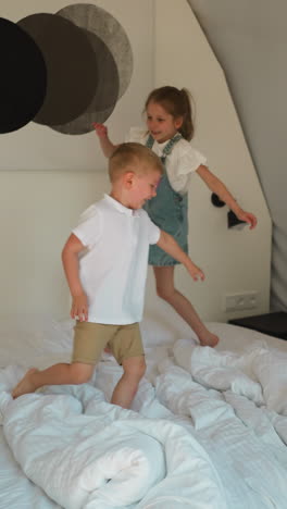 children run on large bed at glamping. joyful little brother and sister plays together in comfortable bedroom. happy healthy kids in hotel room