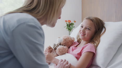 mother visiting daughter lying in bed in hospital ward