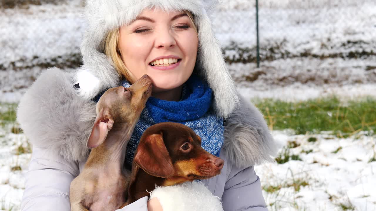 mujer jugando con sus perros pequeños fuera del invierno