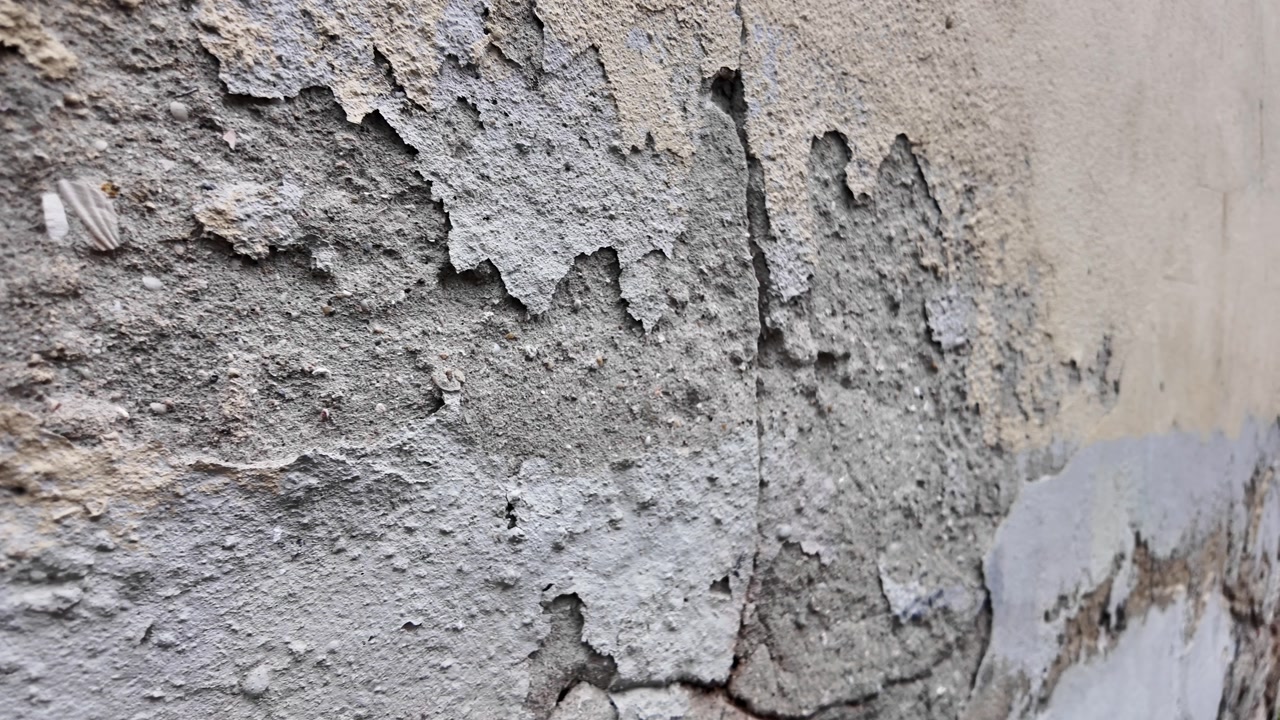 Close-up of Peeling Paint and Crumbling Plaster on an Old Wall