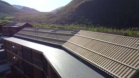 Antena-Que-Pasa-Sobre-Un-Techo-De-Madera-Con-Un-Hermoso-Valle-De-Aarmotsdalen-En-El-Fondo---Amanecer-Sobre-Un-Nuevo-Svoletunet-Construido-En-Myrkdalen-Noruega