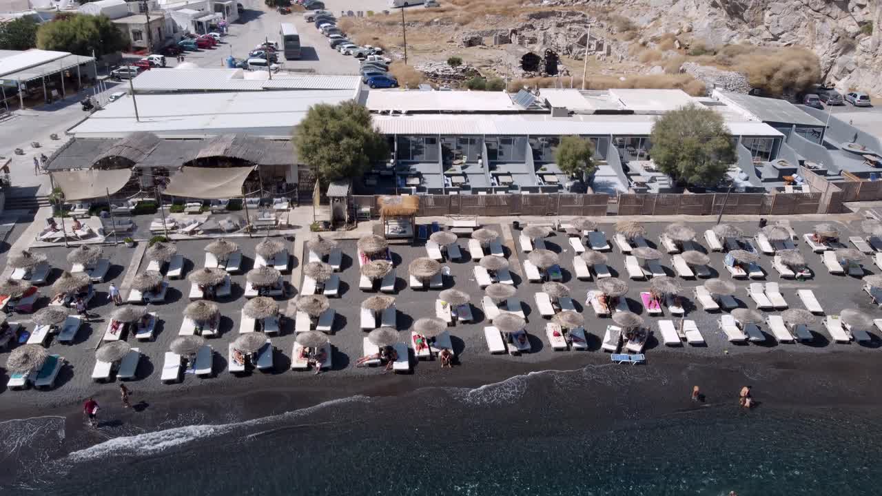 산토리니의 티키 오두막과 관광객들로 가득 찬 페리사 해변의 공중 슬라이딩