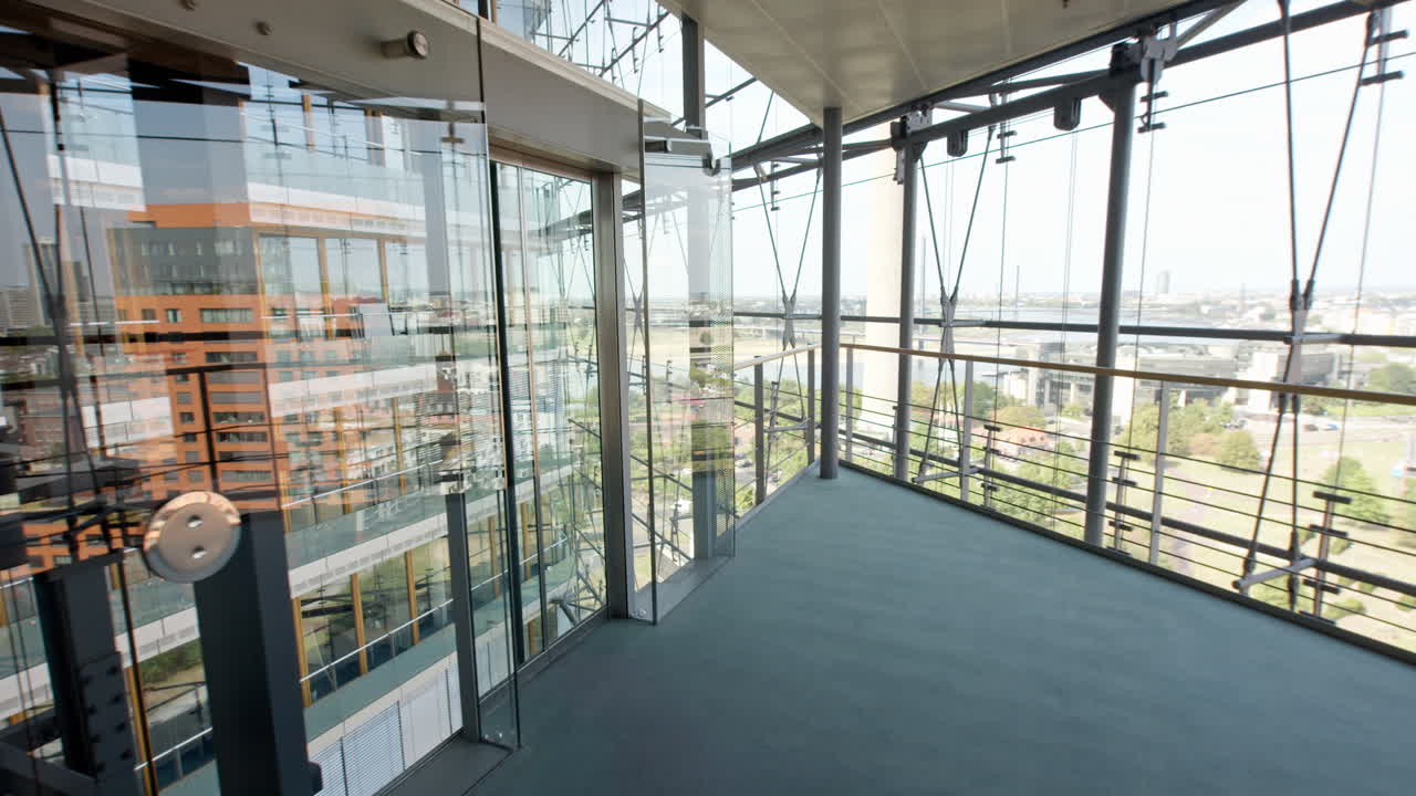High-resolution Video from a high floor inside D&uuml;sseldorf's Stadttor, featuring extensive glass architecture with reflections of another building, captured in good weather