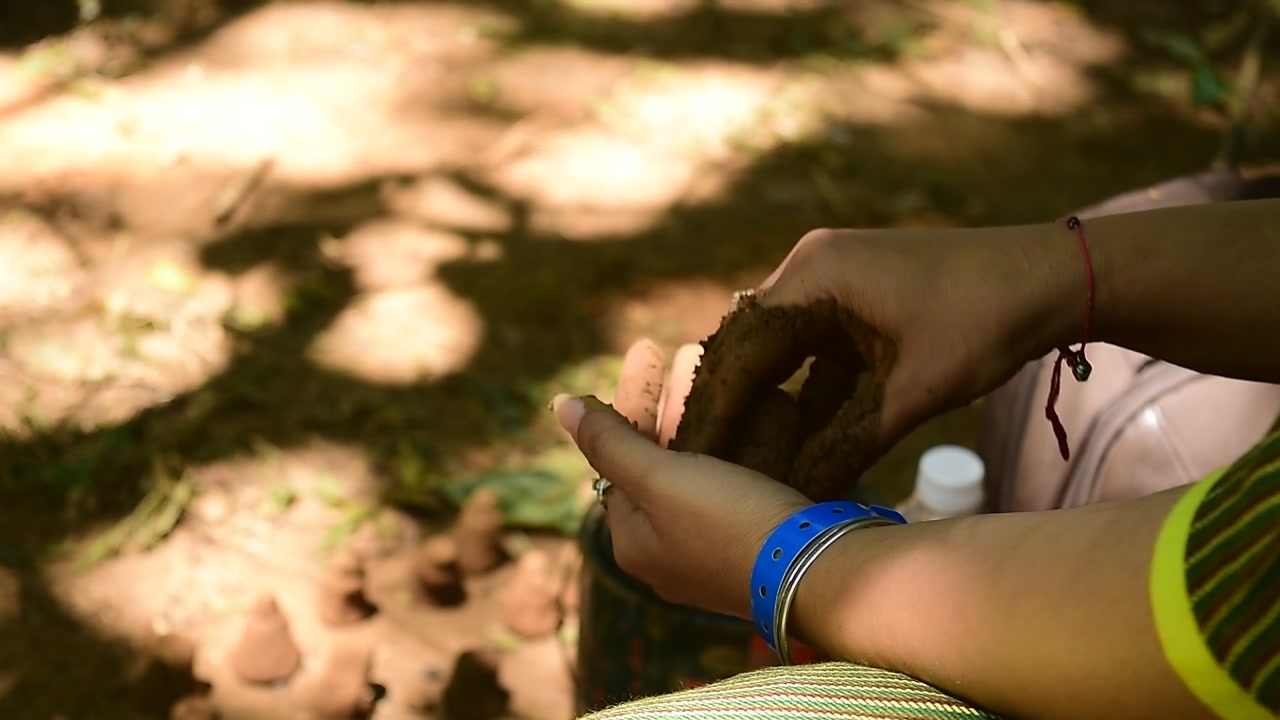 A student moulding natural clay using her hands at a workshop conducted during an architectural college fest.