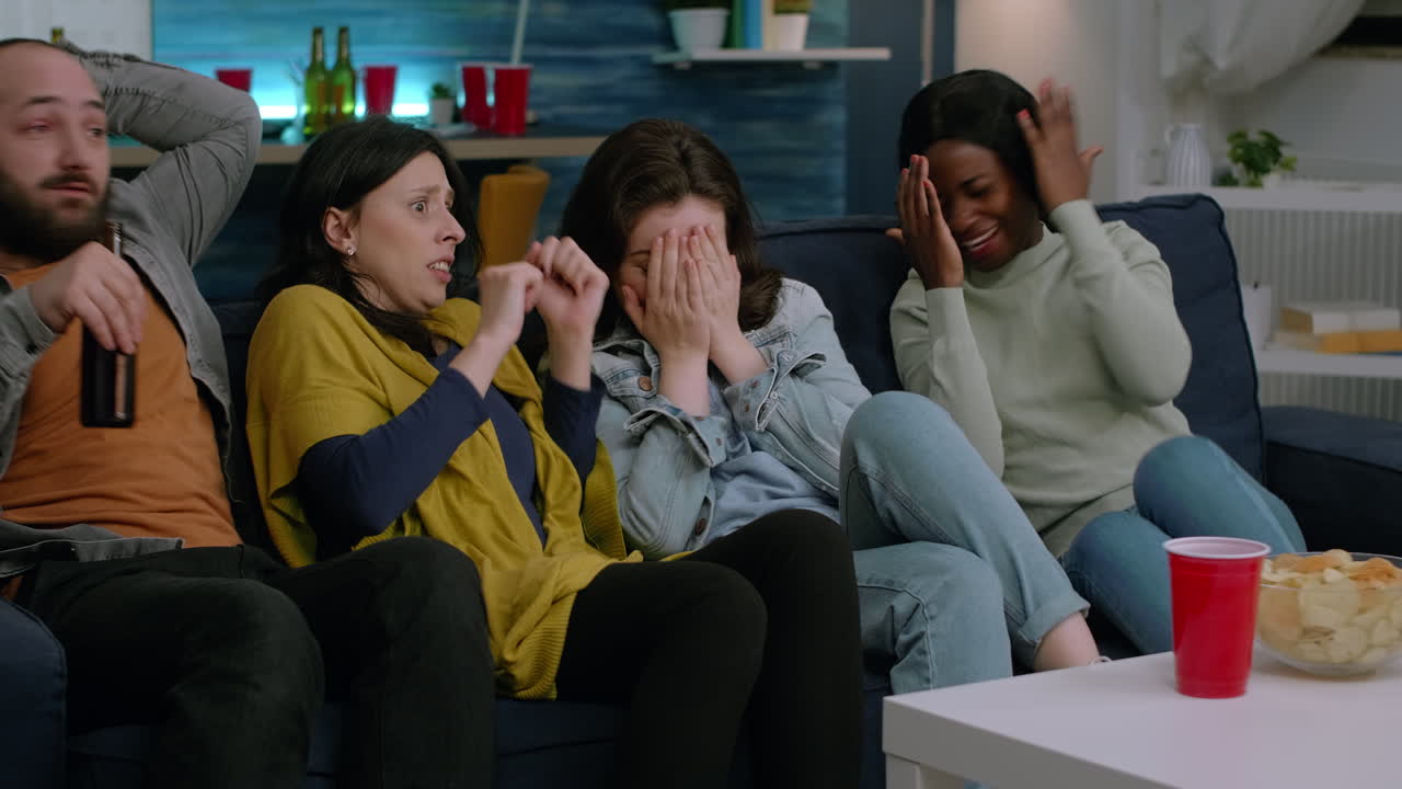 Group of multi-ethnic watching at terrifying movie on television