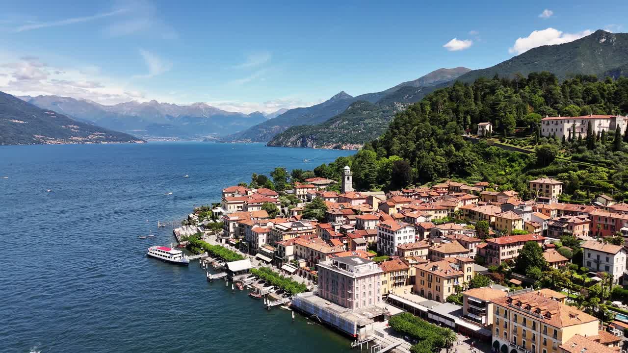 Bellagio town with its traditional buildings and bell tower overlooking the deep blue waters of Lake Como, surrounded by lush green hills and distant Italian Alps